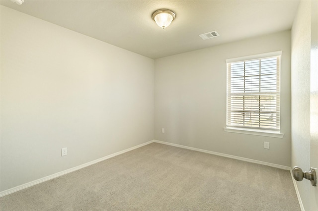 empty room with light carpet, visible vents, and baseboards