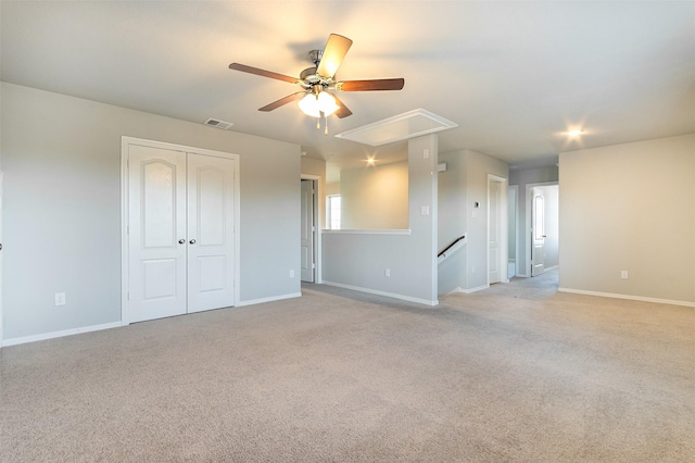 unfurnished room featuring light carpet, attic access, and baseboards