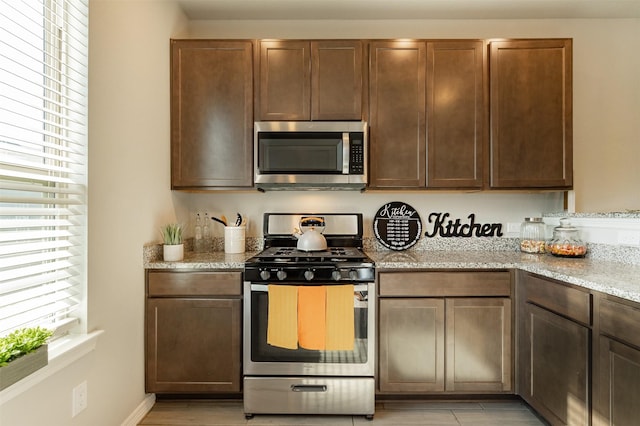 kitchen featuring stainless steel appliances, a wealth of natural light, and light stone counters