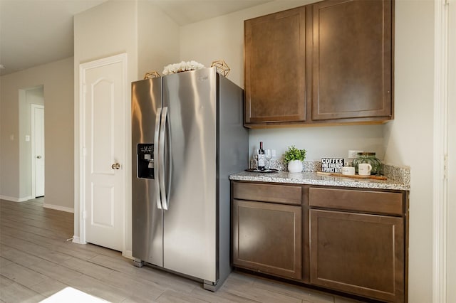 kitchen with light stone counters, wood tiled floor, baseboards, and stainless steel fridge with ice dispenser