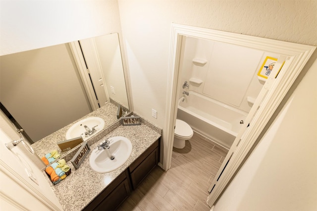 bathroom with a textured wall, vanity, toilet, and wood tiled floor