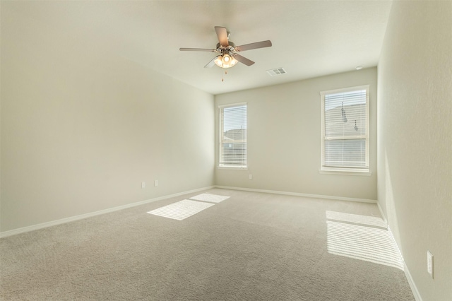 carpeted spare room with a healthy amount of sunlight, baseboards, and a ceiling fan