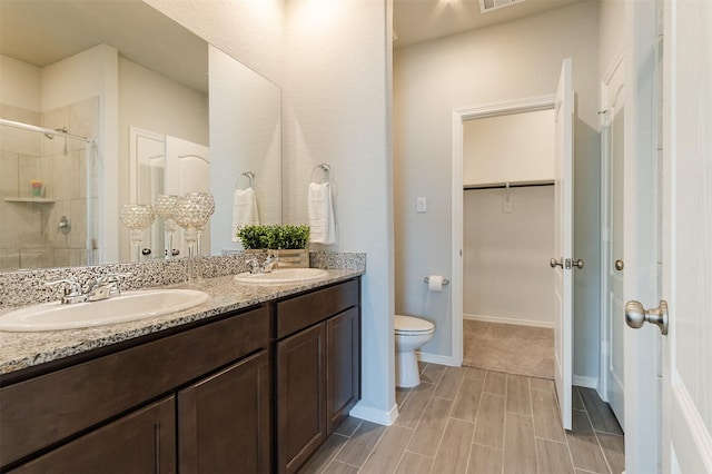 full bathroom with a spacious closet, a stall shower, a sink, and toilet