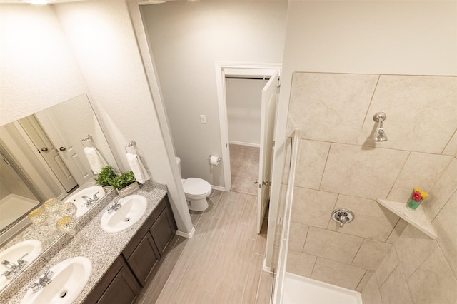 full bathroom featuring double vanity, a sink, toilet, and a shower stall