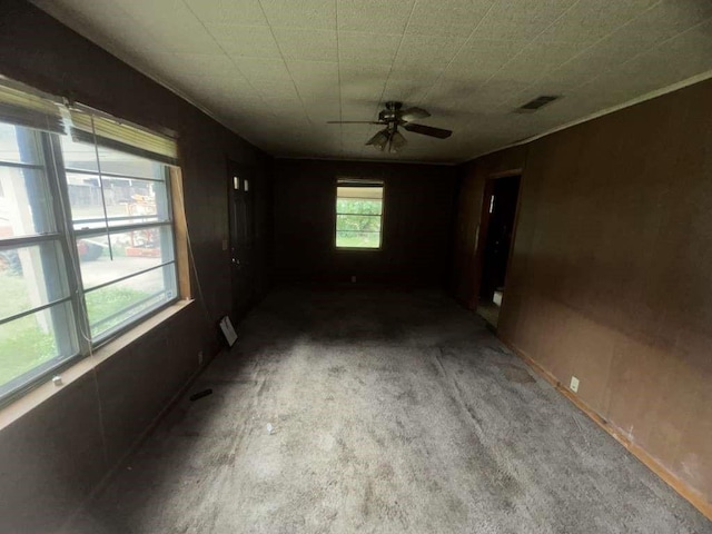 unfurnished room with carpet floors, visible vents, and ceiling fan