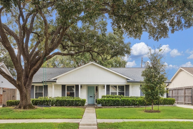 single story home with roof with shingles, fence, a front lawn, and brick siding