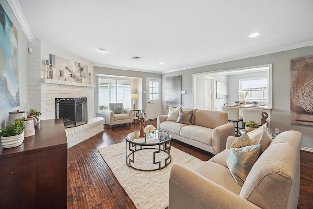 living area featuring visible vents, hardwood / wood-style floors, crown molding, a brick fireplace, and recessed lighting