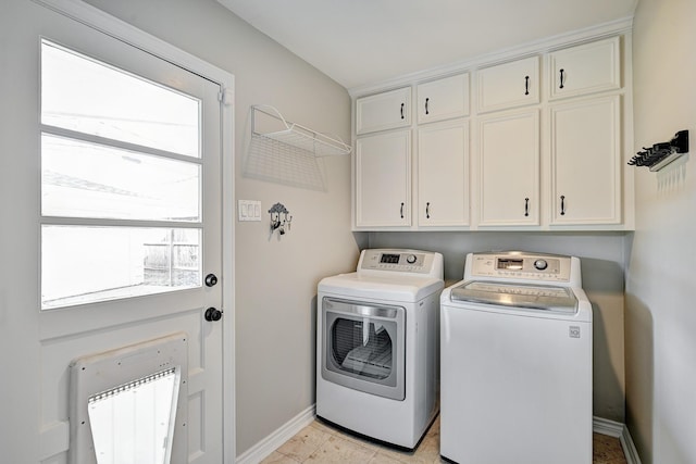 clothes washing area featuring baseboards, cabinet space, and washer and dryer