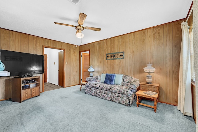 living area featuring a ceiling fan, carpet, and wooden walls