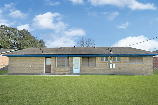 back of house featuring brick siding and a lawn