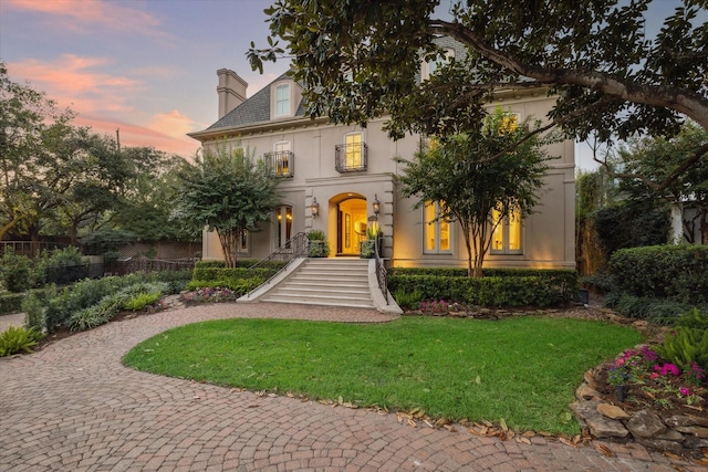 view of front of property with stairway, a lawn, a chimney, and stucco siding