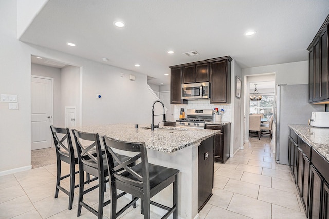 kitchen with visible vents, a breakfast bar area, a sink, stainless steel appliances, and backsplash