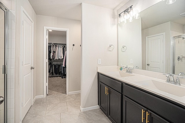 bathroom with double vanity, a stall shower, a sink, and tile patterned floors