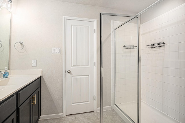 bathroom with baseboards, tiled shower, vanity, and tile patterned floors