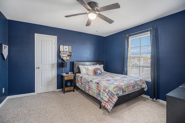 carpeted bedroom with ceiling fan, baseboards, and a textured wall