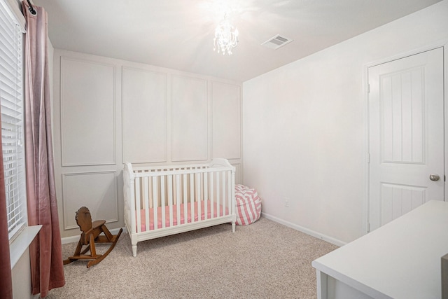 bedroom with a chandelier, light carpet, visible vents, baseboards, and a nursery area