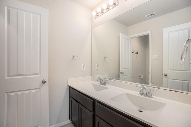 bathroom featuring double vanity, a sink, visible vents, and baseboards