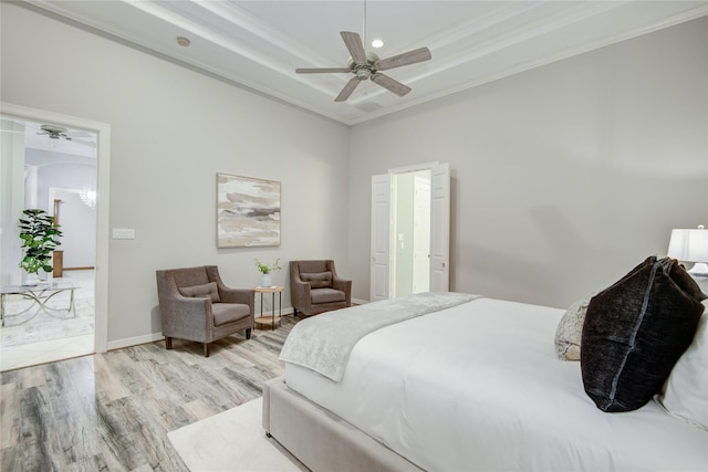 bedroom with baseboards, a raised ceiling, a ceiling fan, ornamental molding, and wood finished floors