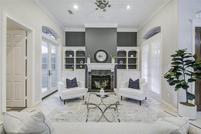 living room with built in features, a fireplace, visible vents, ornamental molding, and baseboards