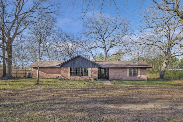 view of front of house featuring a front lawn, a chimney, fence, and brick siding