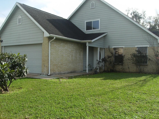 back of property with a yard, brick siding, an attached garage, and a shingled roof