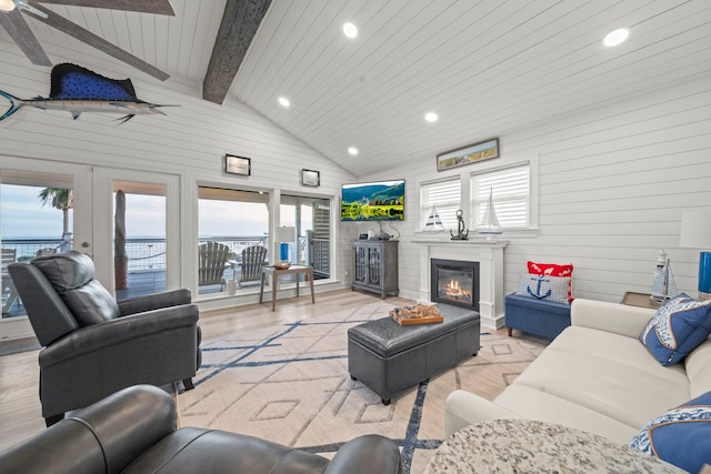 living area featuring a glass covered fireplace, beamed ceiling, wood walls, and light wood finished floors