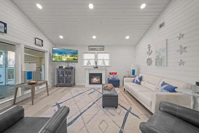 living area featuring lofted ceiling, a glass covered fireplace, light wood finished floors, and recessed lighting