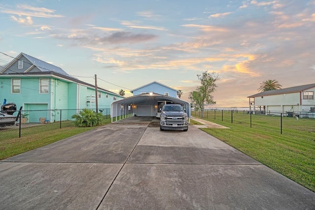 view of front of home with concrete driveway, fence, a carport, and a yard