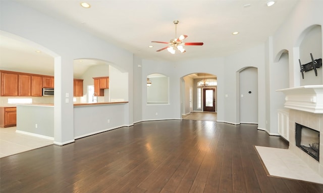 unfurnished living room featuring a ceiling fan, baseboards, a fireplace, recessed lighting, and hardwood / wood-style flooring