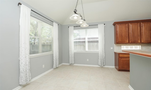 unfurnished dining area featuring vaulted ceiling, light tile patterned floors, and baseboards