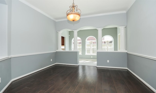 spare room with decorative columns, baseboards, wood finished floors, and ornamental molding