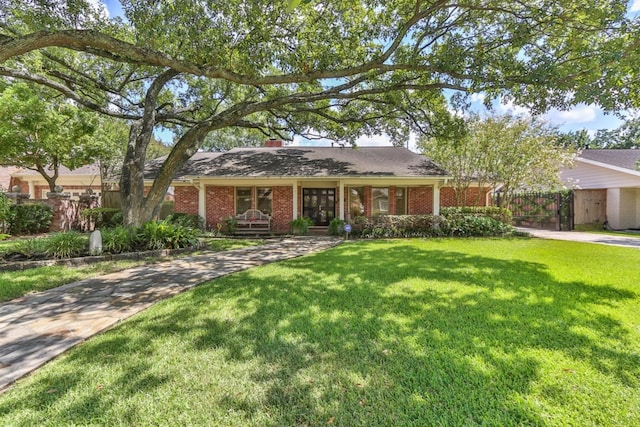 single story home featuring a front yard, fence, brick siding, and driveway