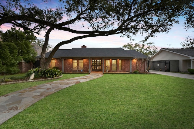 ranch-style house with driveway, a gate, a front yard, brick siding, and a chimney