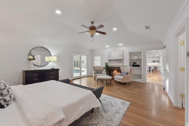 bedroom featuring visible vents, light wood-style floors, a lit fireplace, crown molding, and access to exterior