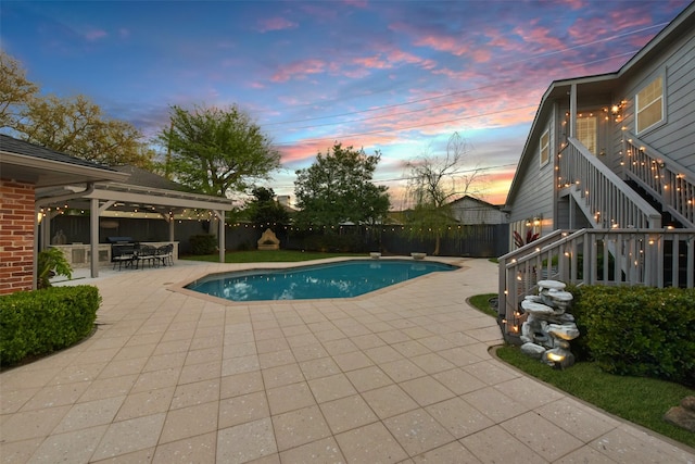 pool at dusk with a fenced in pool, stairs, a fenced backyard, a patio area, and a diving board