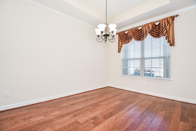 unfurnished room featuring baseboards, a tray ceiling, wood finished floors, and an inviting chandelier