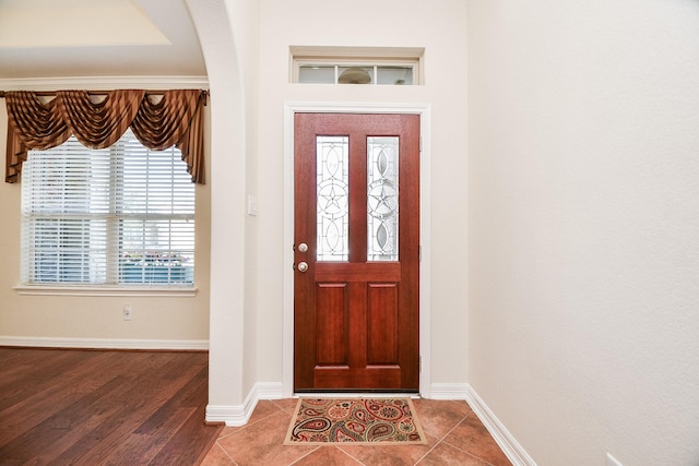 entryway featuring baseboards, arched walkways, and tile patterned floors