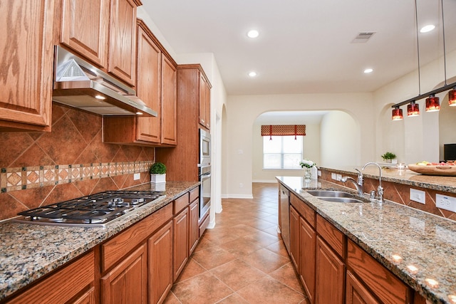 kitchen featuring light stone counters, stainless steel appliances, visible vents, a sink, and under cabinet range hood