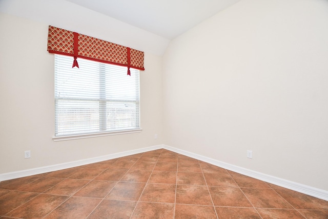 spare room with lofted ceiling, tile patterned flooring, and baseboards