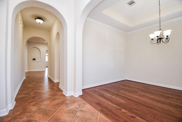 interior space with crown molding, a raised ceiling, visible vents, an inviting chandelier, and baseboards