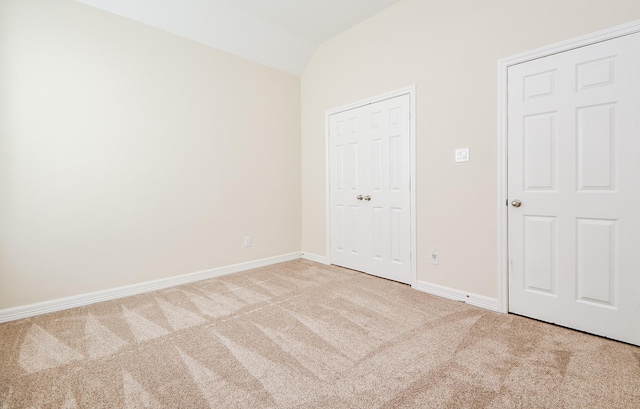 unfurnished bedroom featuring lofted ceiling, carpet, and baseboards