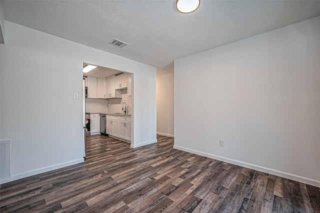 unfurnished living room featuring dark wood-style flooring, visible vents, a sink, and baseboards