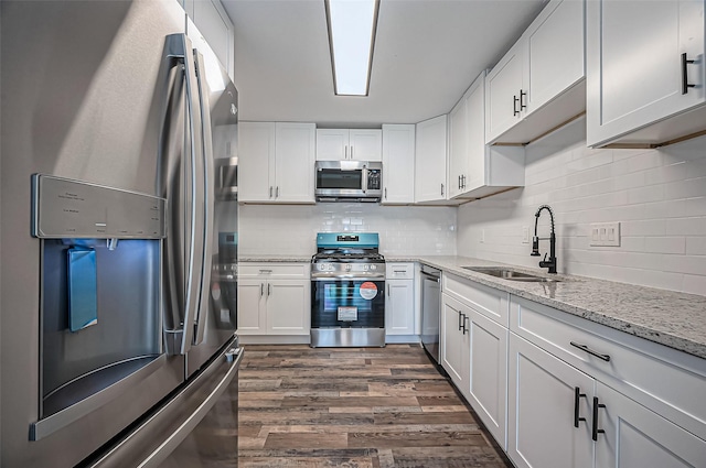 kitchen featuring stainless steel appliances, dark wood-style flooring, a sink, and white cabinetry