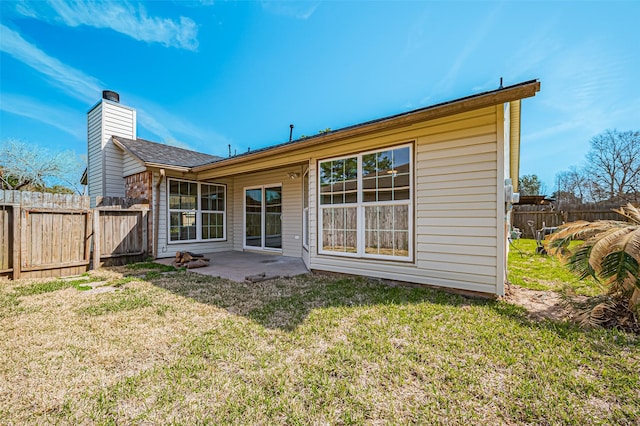 rear view of house featuring a chimney, fence, a lawn, and a patio