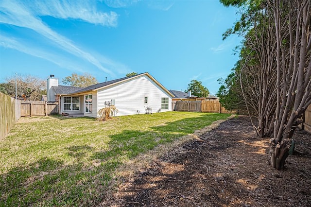 back of house with a yard, a chimney, and a fenced backyard