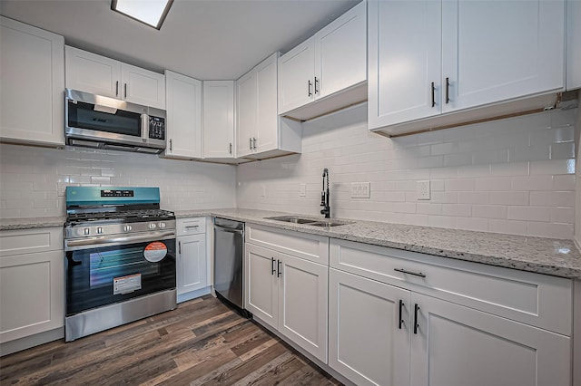 kitchen featuring stainless steel appliances, tasteful backsplash, dark wood-type flooring, white cabinets, and a sink