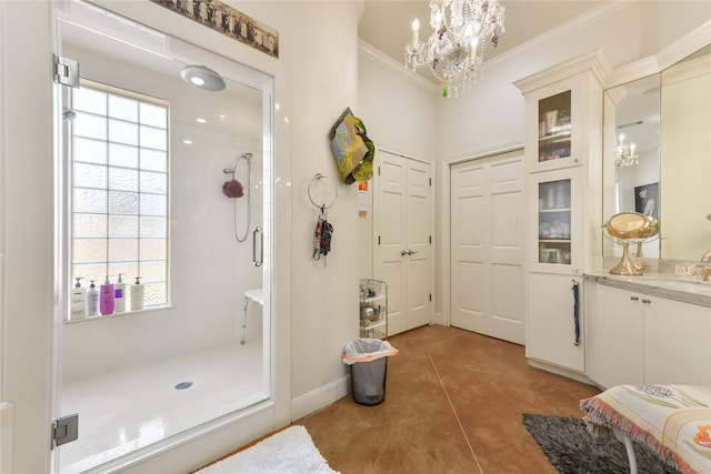 bathroom featuring an inviting chandelier, ornamental molding, a stall shower, vanity, and baseboards