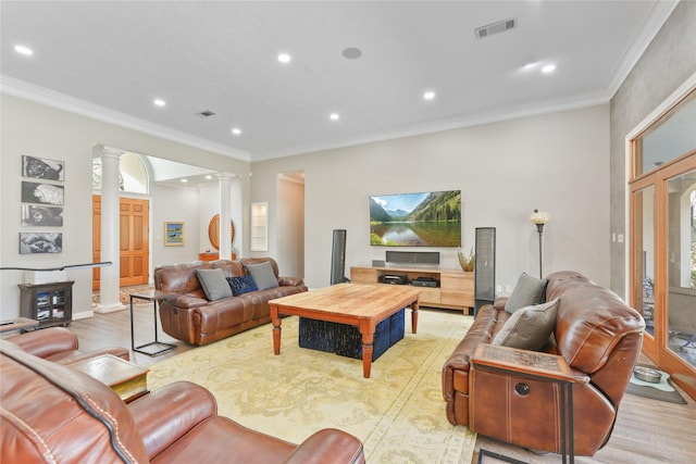 living area with crown molding, visible vents, and decorative columns