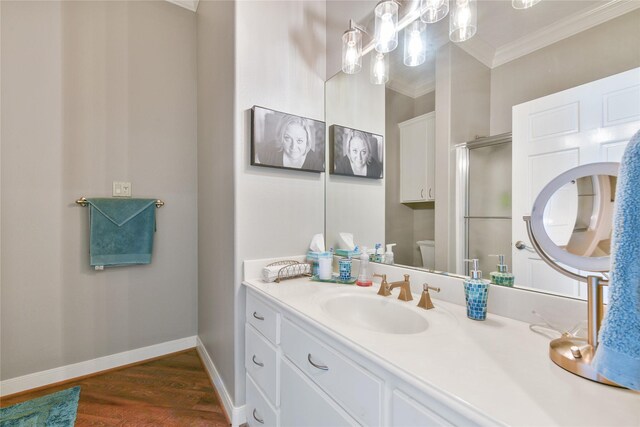 bathroom with crown molding, toilet, vanity, wood finished floors, and baseboards