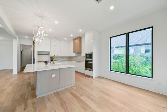 kitchen featuring stainless steel appliances, tasteful backsplash, white cabinets, and modern cabinets